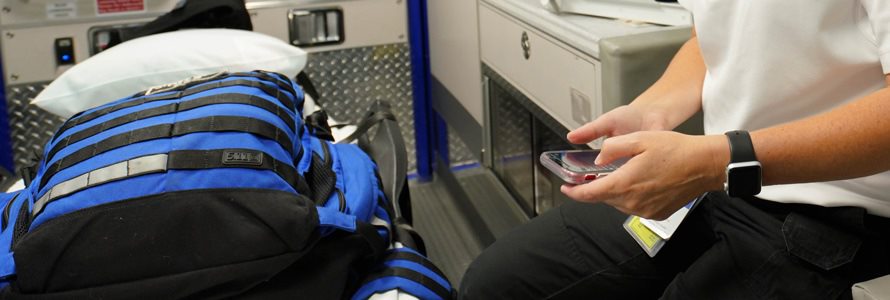 First responder in an ambulance holding a cell phone