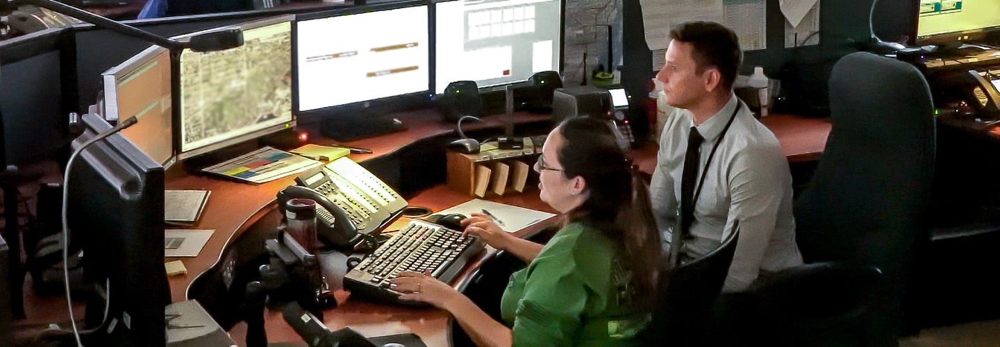 Two Miami-Dade dispatchers look at screens of information in their ECC