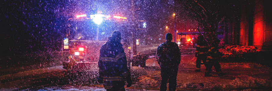 Firefighter standing by fire engine at snow covered city street