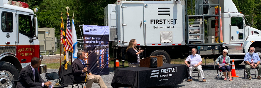 Public safety stakeholders; FirstNet Authority and FirstNet, Built with AT&T, staff; and state politicians sit in front of a fire truck and a deployable satellite truck.