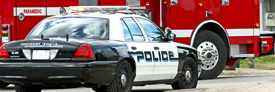 A police cruiser with lit sirens in front of a paramedic vehicle.