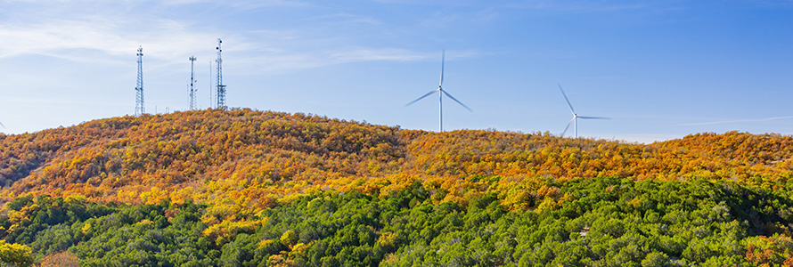 Wind turbines sit among trees in the Turner Falls area