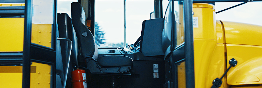 School bus with doors open showing the driver’s seat.