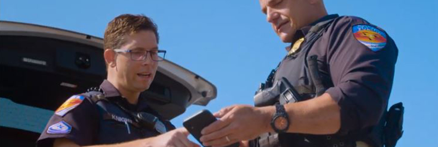 Two Town of Duck officers look at a smartphone 