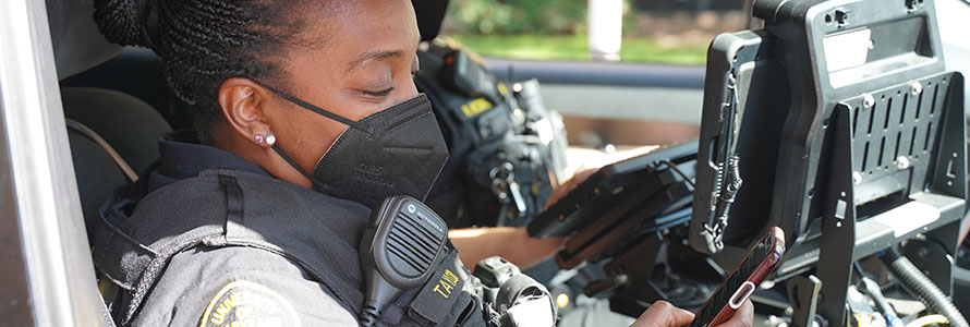 Two University of Maryland, Baltimore campus police officers checking out a laptop in the front of their parked cruiser