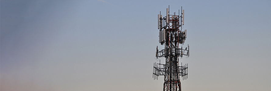 A cell tower and blue sky with wispy cloud