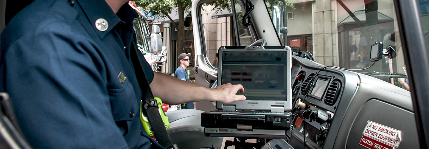 A paramedic using a laptop in the front seat of an ambulance