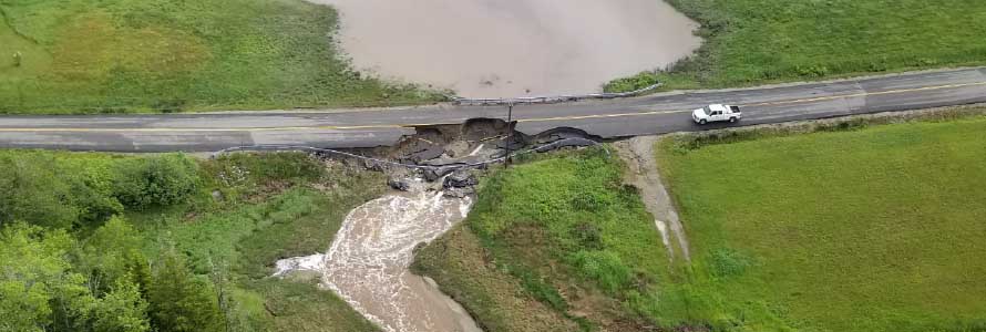 Aerial view of pickup truck near washed out road and flooded grass