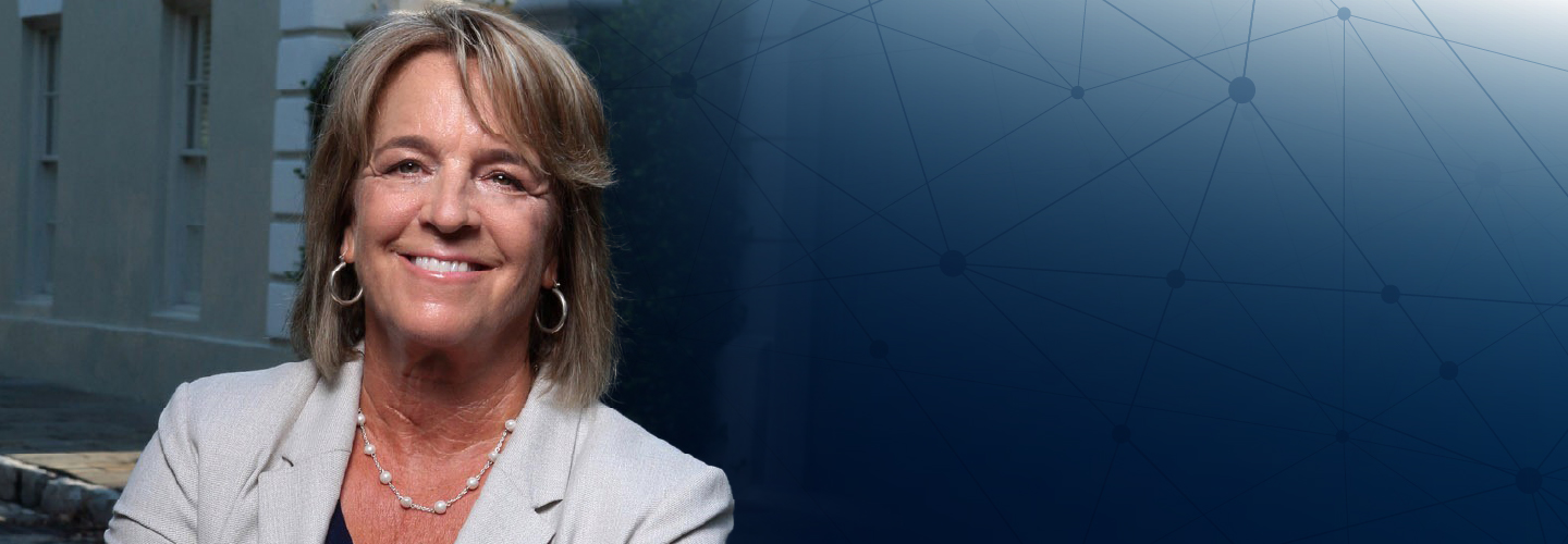 A headshot of FirstNet Authority Board Member Kristin Graziano, a backdrop of an office building and a series of network connections.