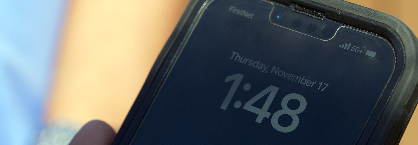 Close-up of smartphone. On screen: “FirstNet. 5G+. Tuesday, November 17. 1:48”