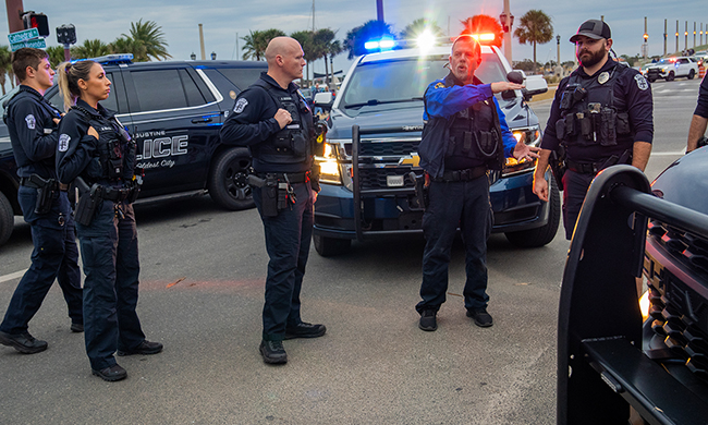 Six police officers talking in front of three police vehicles at an intersection in St. Augustine, Florida  