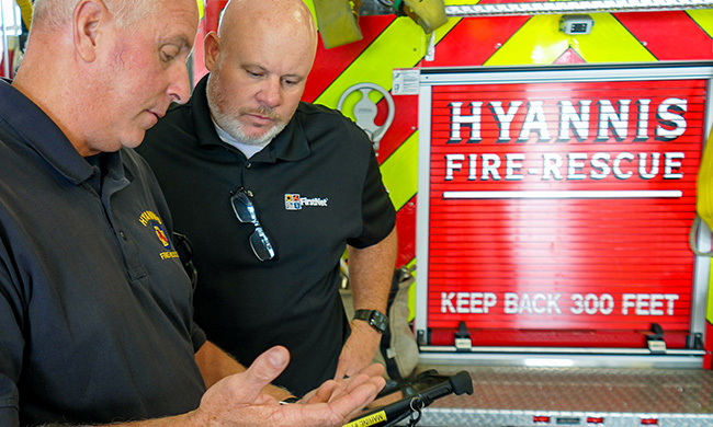 A fire fighter from Hyannis asks a FirstNet Authority staff member a question while holding a tablet