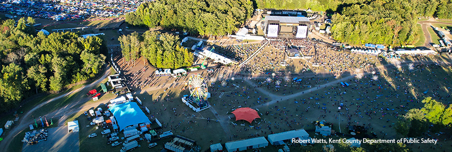 An aerial view of the Firefly Musical Festival grounds, crowds of people at several live music stages around the grounds, a packed parking lot