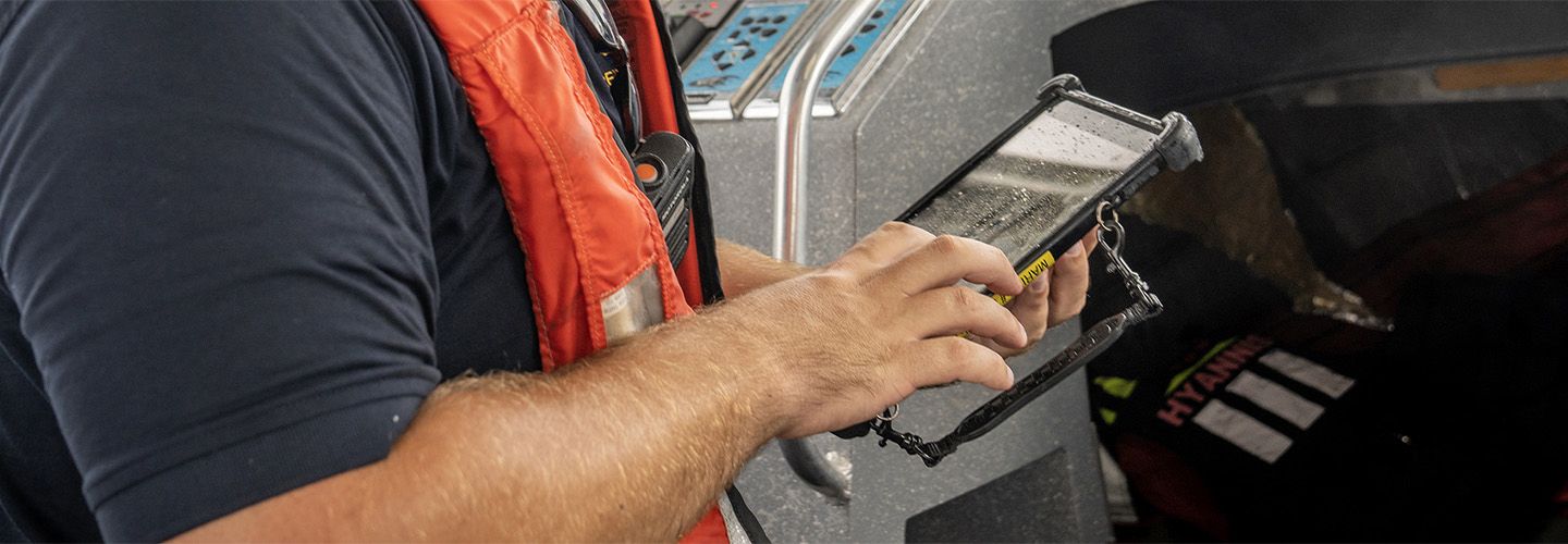 A Hyannis firefighter uses a tablet on a boat