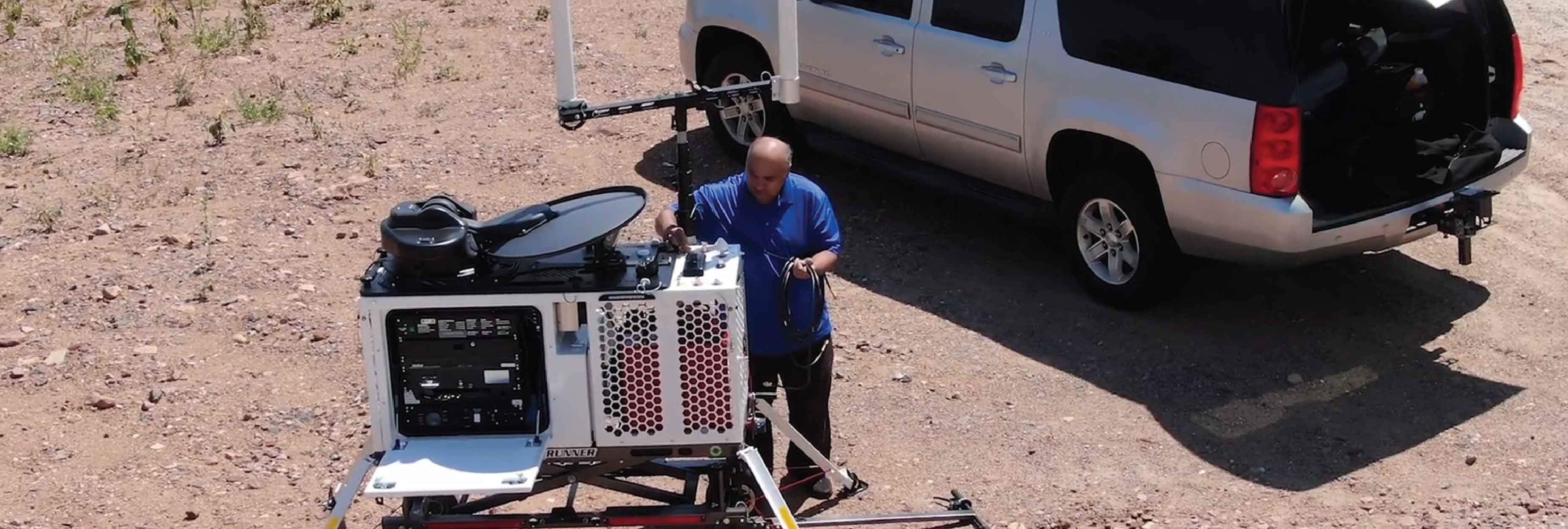 A man sets up a Compact Rapid Deployable for use in a desert area 