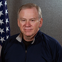 Headshot of John Hunt. He sits in front of an American flag.