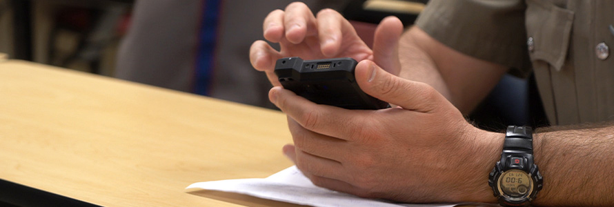 The hands of a first responder using a smartphone at a table. 