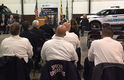 During an event marking one year of FirstNet in the State of Maryland, Sheriff Mullendore speaks at a podium in front of police vehicles