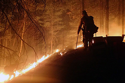 A firefighter monitors Sugar Pine/Miles Fire in Oregon at night. Photo credit: U.S. Forest Service – Pacific Northwest Region, July 30, 2018.