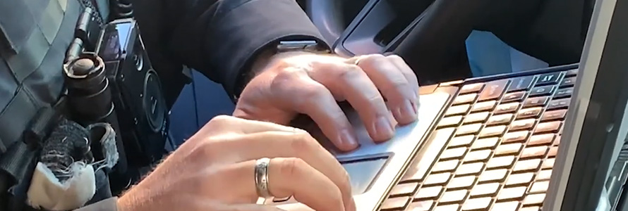 A law enforcement officer types on a computer.    