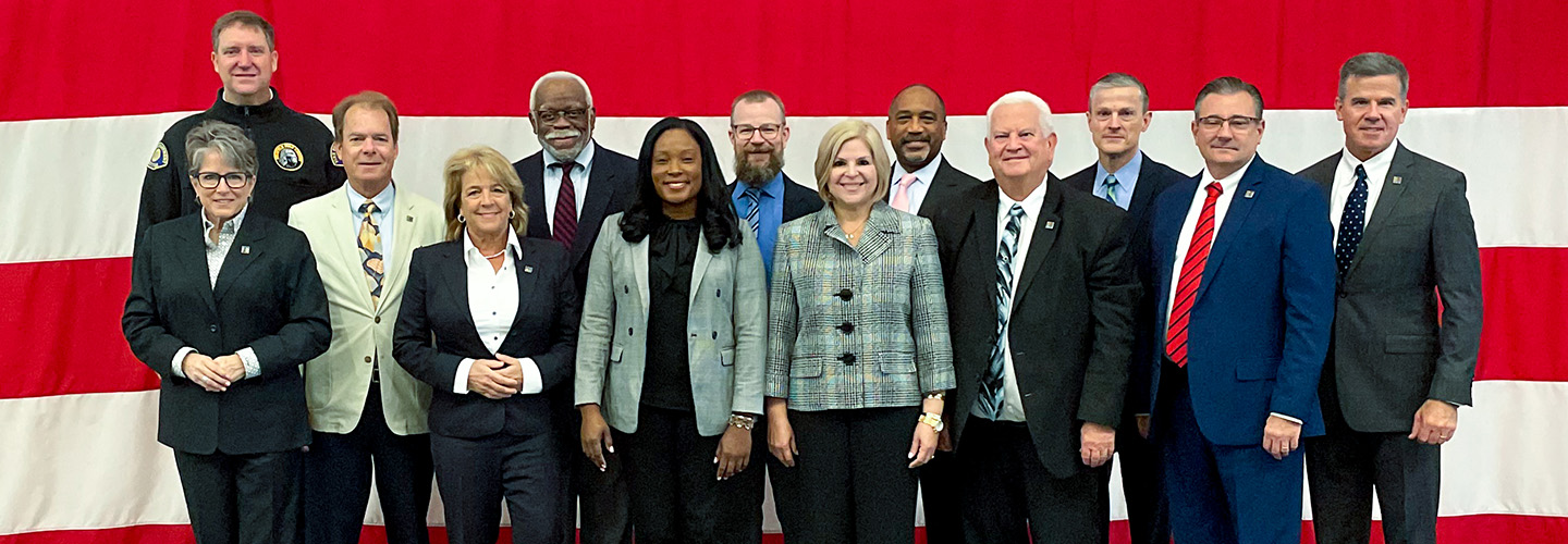 FirstNet Authority Board members stand in front of an American flag before the August 2023 meeting