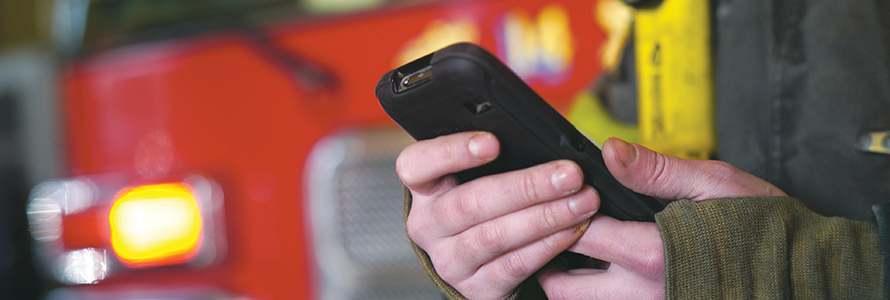 Firefighter holds smartphone in front of fire vehicle