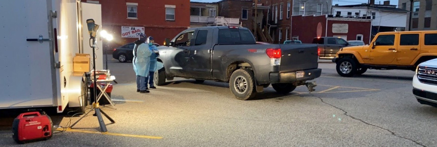 Medical professionals stand by a pickup truck at a COVID-19 testing site.