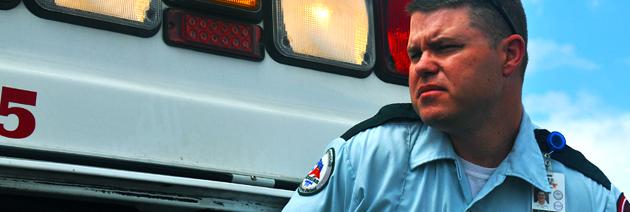 Emergency medical services professional stands in front of ambulance