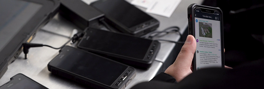 A Washington County law enforcement officer holds a FirstNet enabled device near several other devices being charged