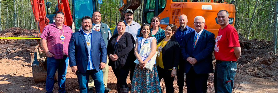 Eleven representatives who broke ground at a cell tower on the Red Cliff reservation stand in front of an excavator.