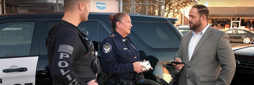 Ironton Police Department Chief Pamela Wagner and an Ironton police officer talk with Ironton Mayor Sam Cramblit outside of a police SUV cruiser.