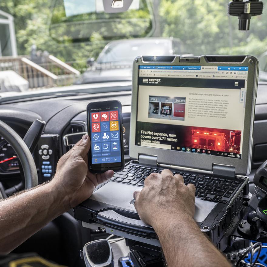A police officer uses FirstNet devices inside of their patrol car