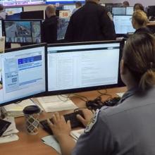 Emergency call ceneter with personel in front of three monitors  