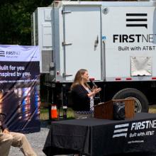 Public safety stakeholders; FirstNet Authority and FirstNet, Built with AT&T, staff; and state politicians sit in front of a fire truck and a deployable satellite truck.