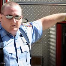 A first responder stands next to an emergency vehicle