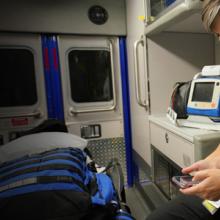 Public Safety First podcast logo; EMS official sits in ambulance and holds smartphone in hand Public Safety First podcast logo; EMS official sits in ambulance and holds smartphone in hand