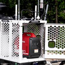 A man wearing a FirstNet shirt looks at a compact rapid deployable that is set up ready for use.