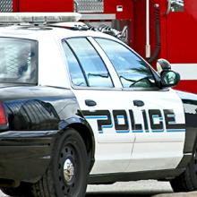 A police cruiser with lit sirens in front of a paramedic vehicle.