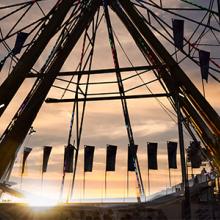 A Ferris wheel backlit by the sunset.