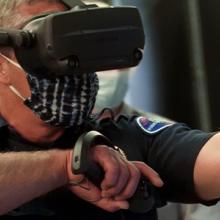 First responder wearing virtual reality glasses and holding controllers and gesticulates forward.