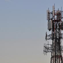 A cell tower and blue sky with wispy cloud