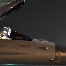 Air Force pilot sits in a jet at night.