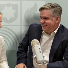 Host Dave Buchanan interviews Amanda Hilliard in front of a microphone on a table