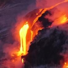 Orange lava flows down the side of a volcano