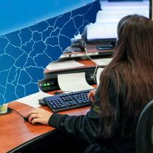 Cell tower; outline of the state of Tennessee; a 9-1-1 telecommunicator at her workstation