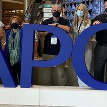 FirstNet Authority staff pose with APCO sign from 2021 conference