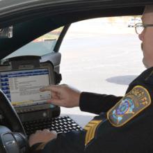 A Brazos County Sheriff's Department officer looks at a screen inside of his patrol car
