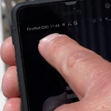 A first responder using a smart phone that is connected to the internet via a FirstNet Compact Rapid Deployable