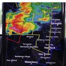 Close up of a phone displaying storm maps in Connecticut