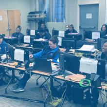 Three photos: first photo is a telecommunicator taking a call from home, second photo is a group of telecommunicators sitting at computers set up on tables, third photo is two telecommunicators looking at a workstation in an emergency communications center. Three photos: first photo is a telecommunicator taking a call from home, second photo is a group of telecommunicators sitting at computers set up on tables, third photo is two telecommunicators looking at a workstation in an emergency communications center.